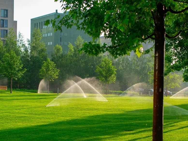 Green and well irrigated lawn with rotor sprinklers running